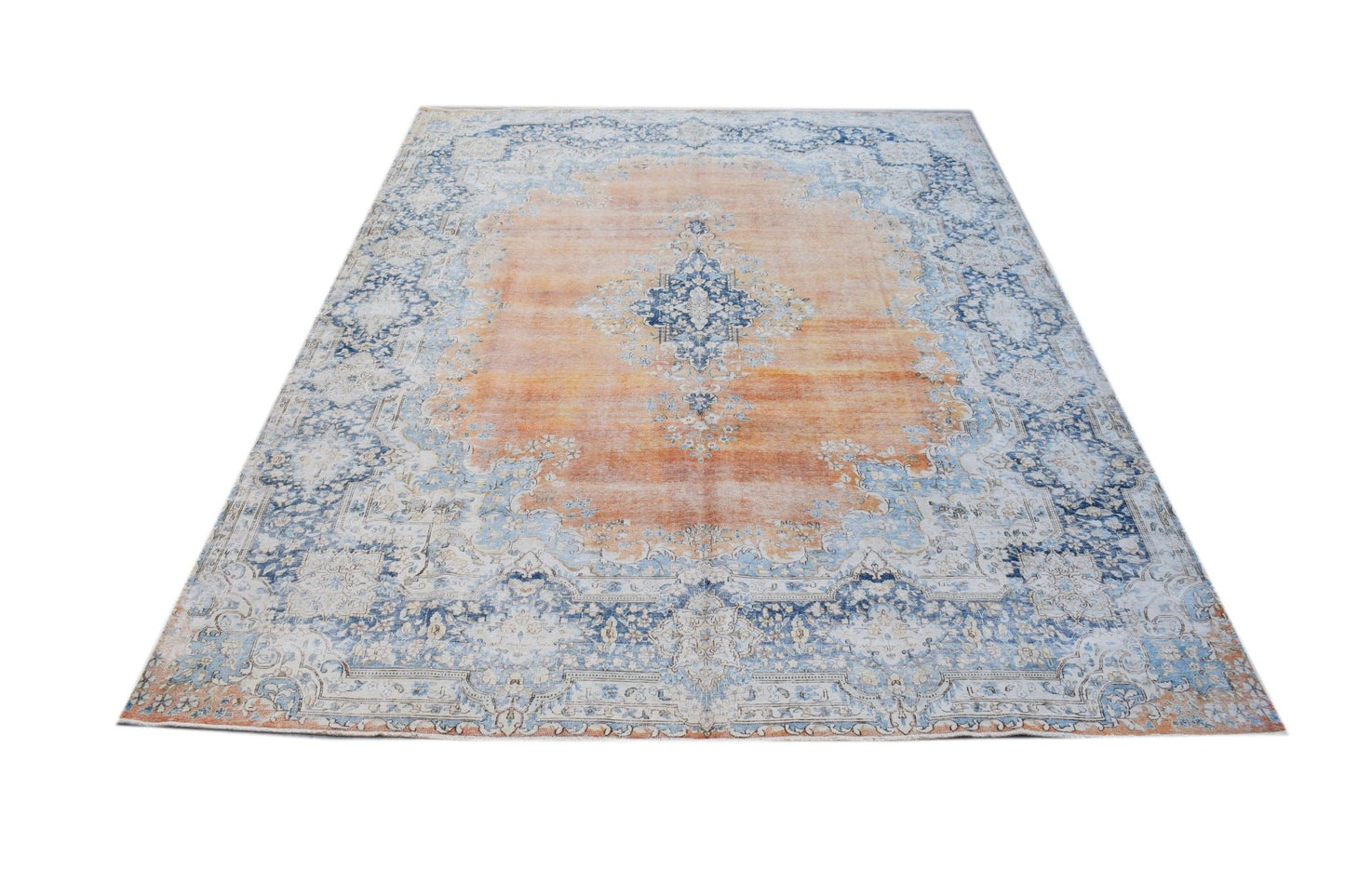 A vintage Persian Kerman rug featuring a central medallion and floral motifs in orange and blue.