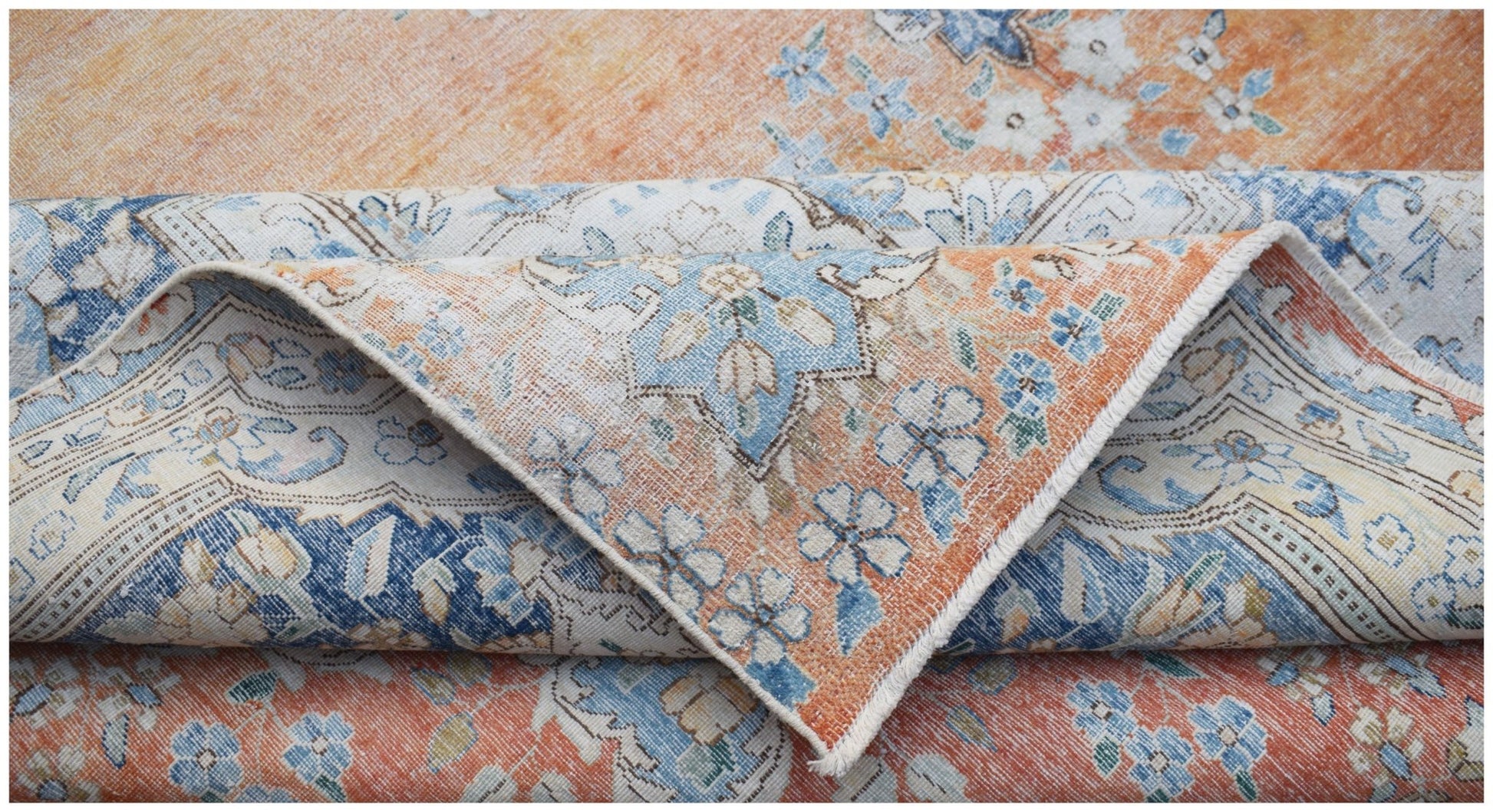 A vintage Persian Kerman rug featuring a floral pattern in shades of orange, blue, and cream.