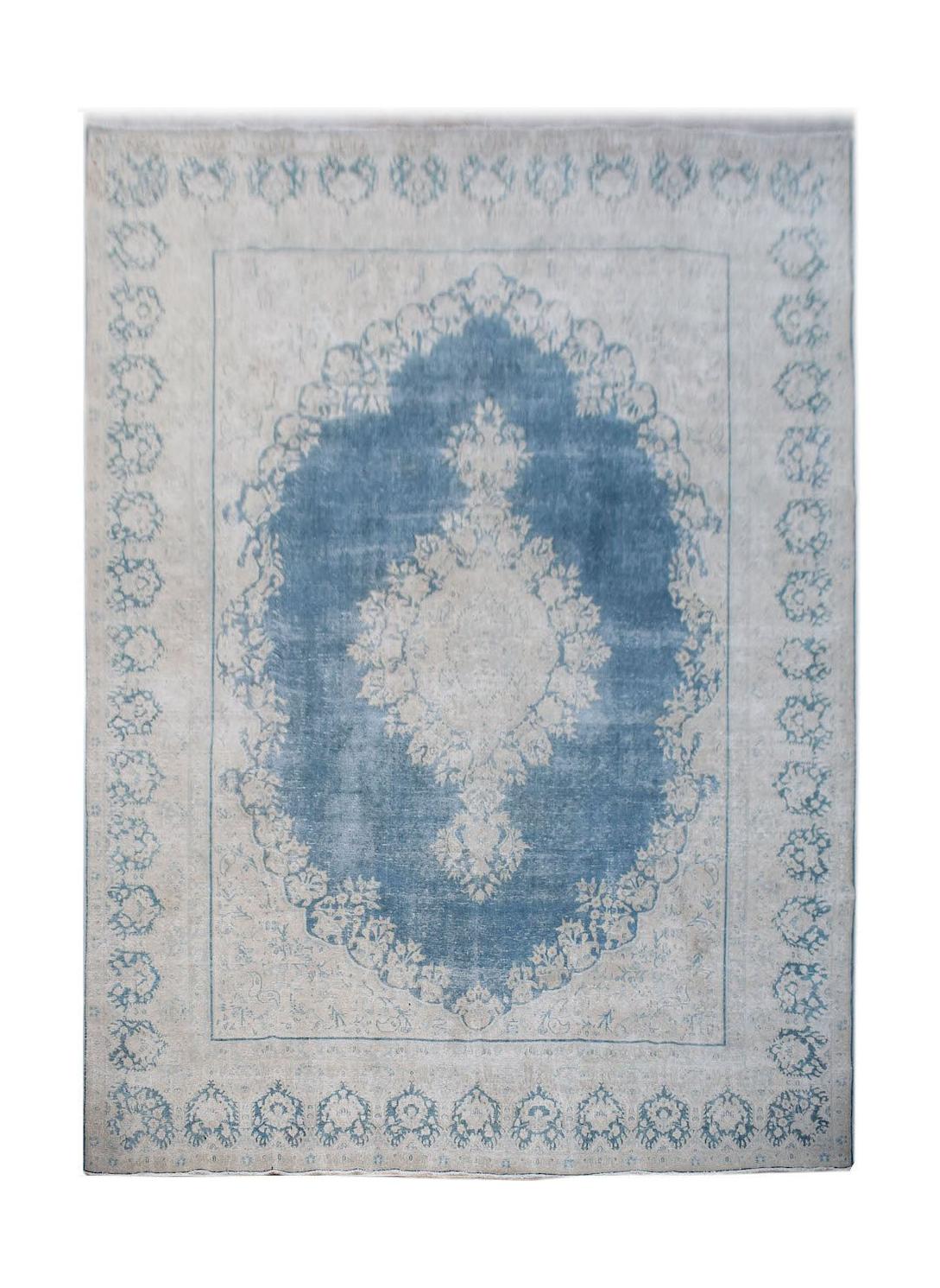 A vintage Persian Kerman rug featuring a central medallion in blue and cream floral patterns.