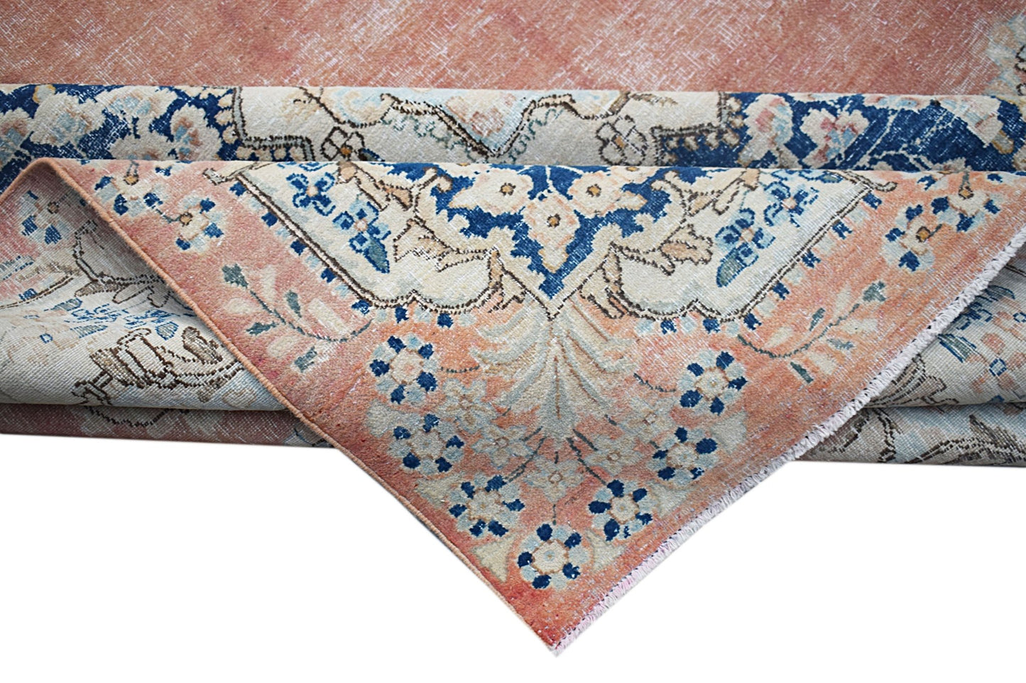 A vintage Persian Kerman rug featuring a floral medallion design in shades of peach and blue.