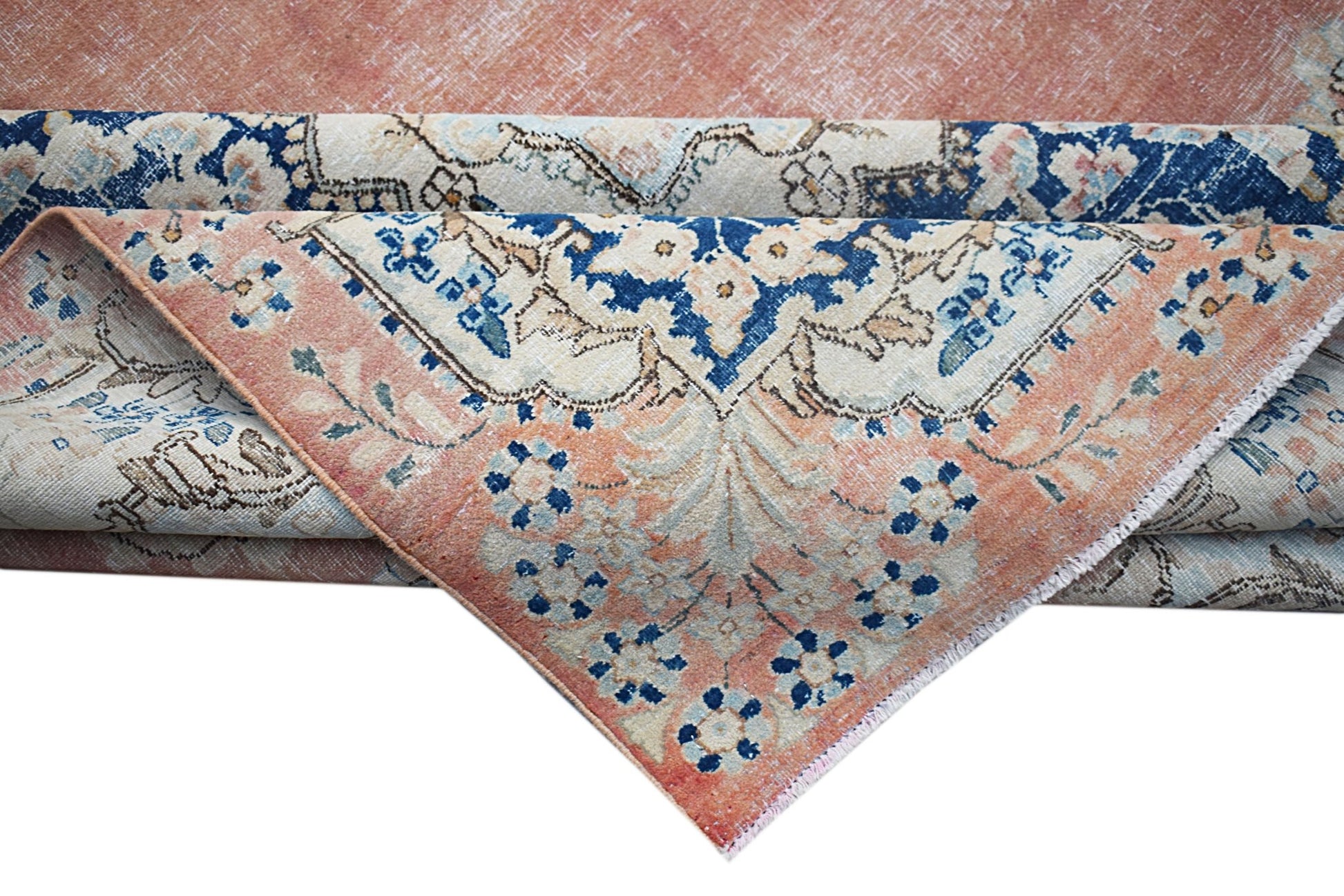 A vintage Persian Kerman rug featuring a floral medallion design in shades of peach and blue.