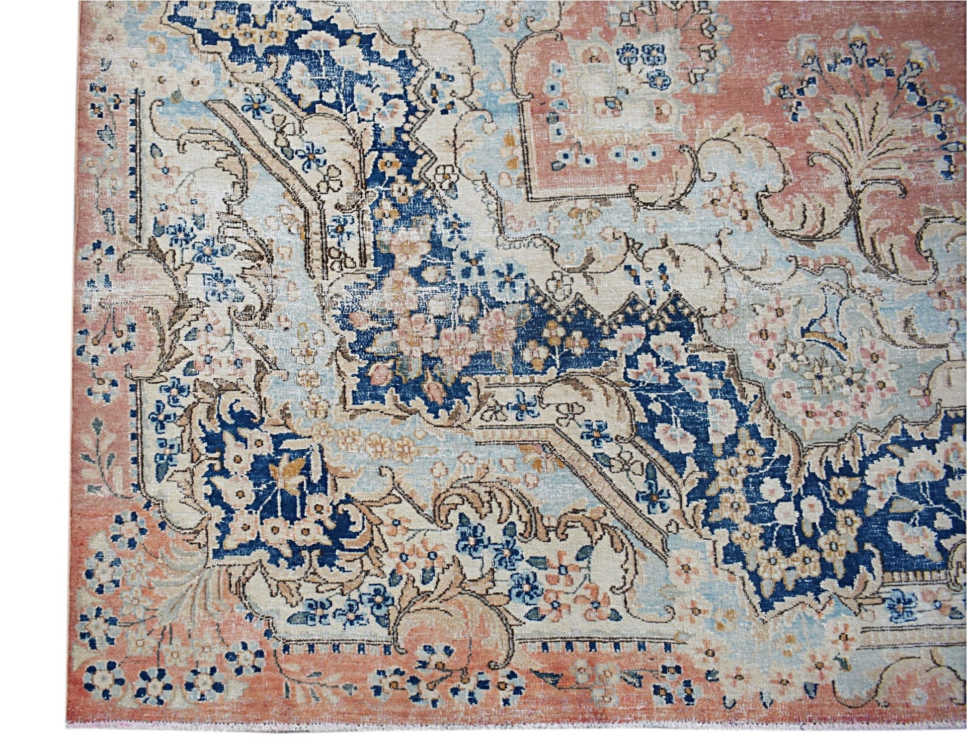 A vintage Persian Kerman rug featuring intricate floral patterns in blue, cream, and soft pink.