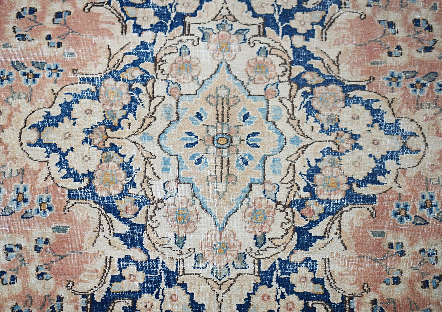 A vintage Persian Kerman rug featuring a central medallion with intricate floral patterns in blue.