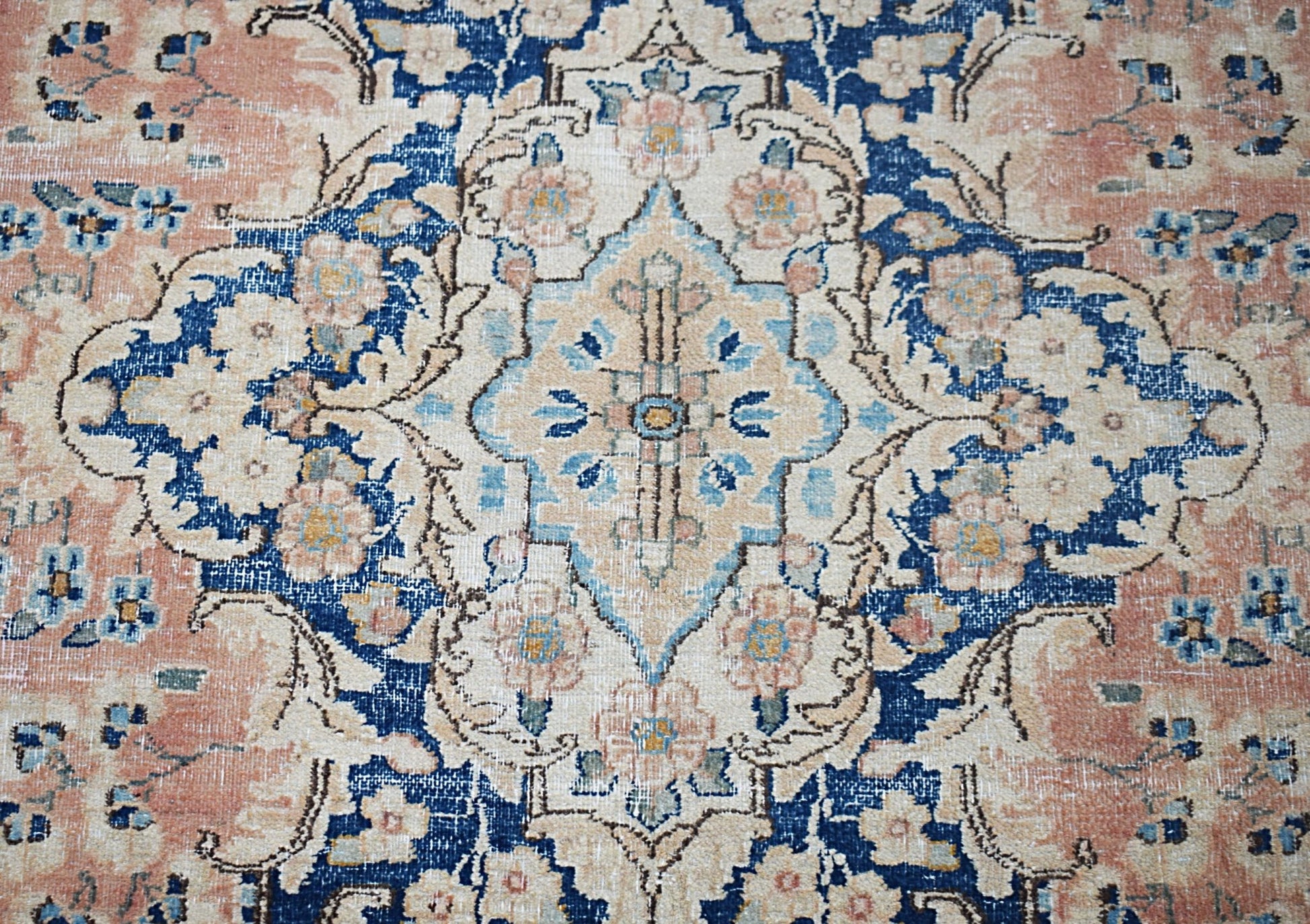 A vintage Persian Kerman rug featuring a central medallion with intricate floral patterns in blue.