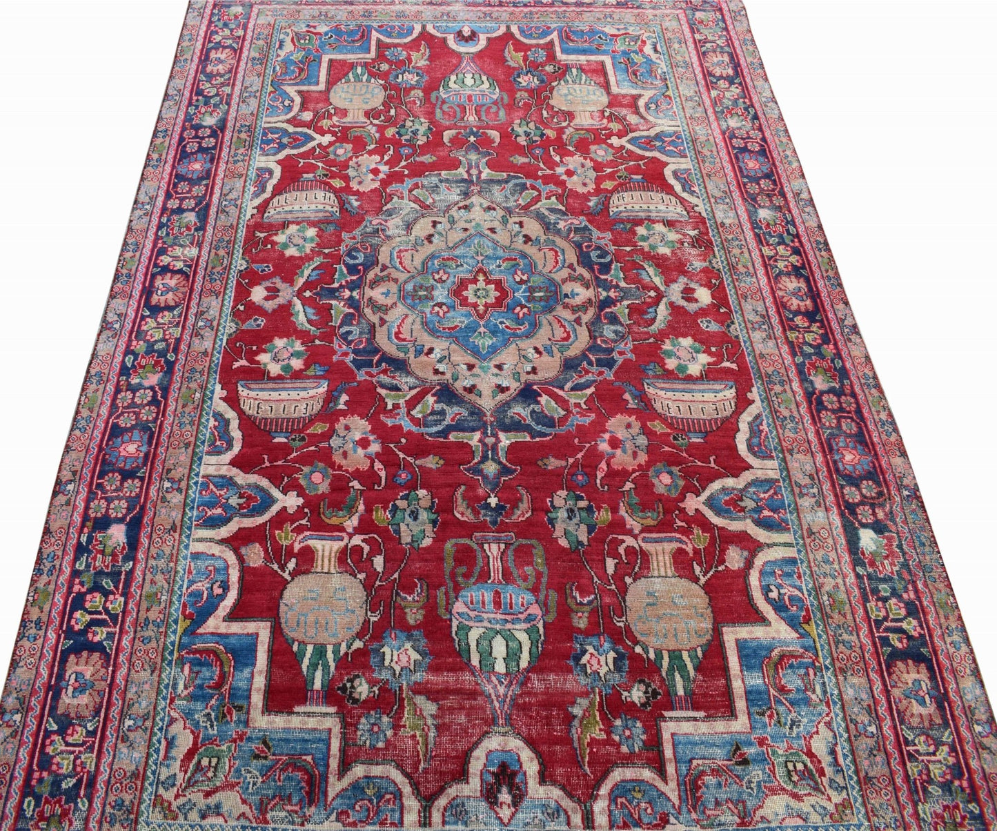 A vintage Persian Tabriz rug featuring a central medallion and intricate floral vase motifs.