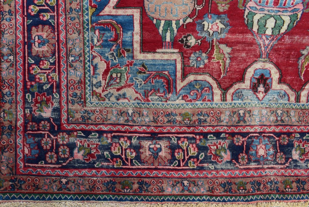 A vintage Persian Tabriz rug featuring an intricate floral medallion design in red and blue tones.
