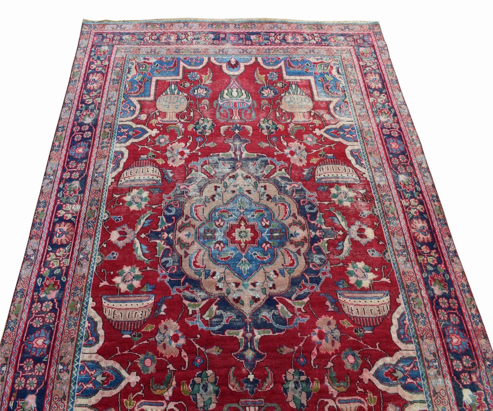 A vintage Persian Tabriz rug featuring a central medallion and intricate floral motifs on red.