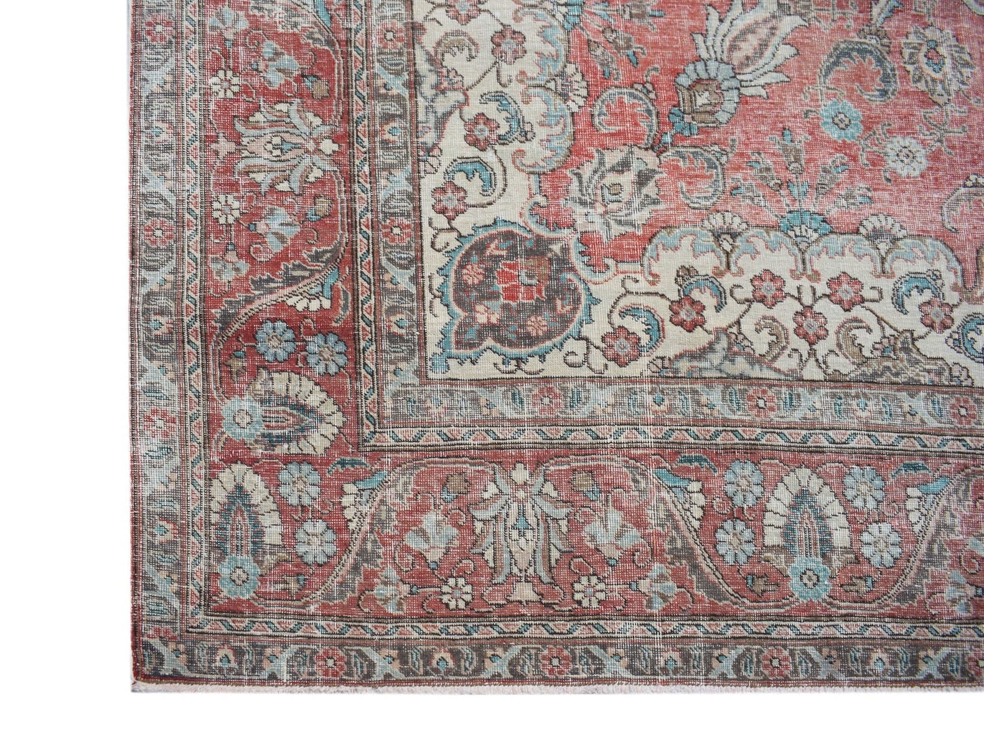 A vintage Persian Tabriz rug featuring intricate floral patterns in red, cream, and blue tones.