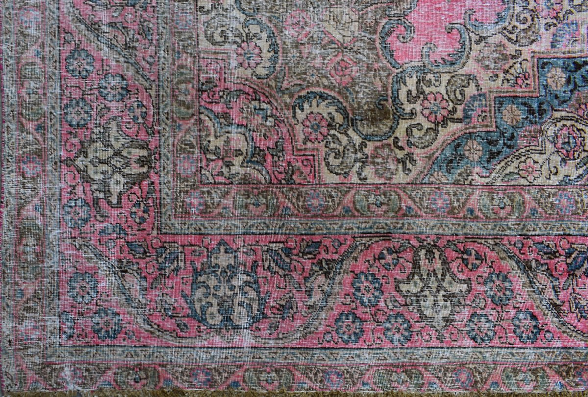 A vintage Persian Tabriz rug featuring intricate floral patterns in shades of pink, blue, and tan.