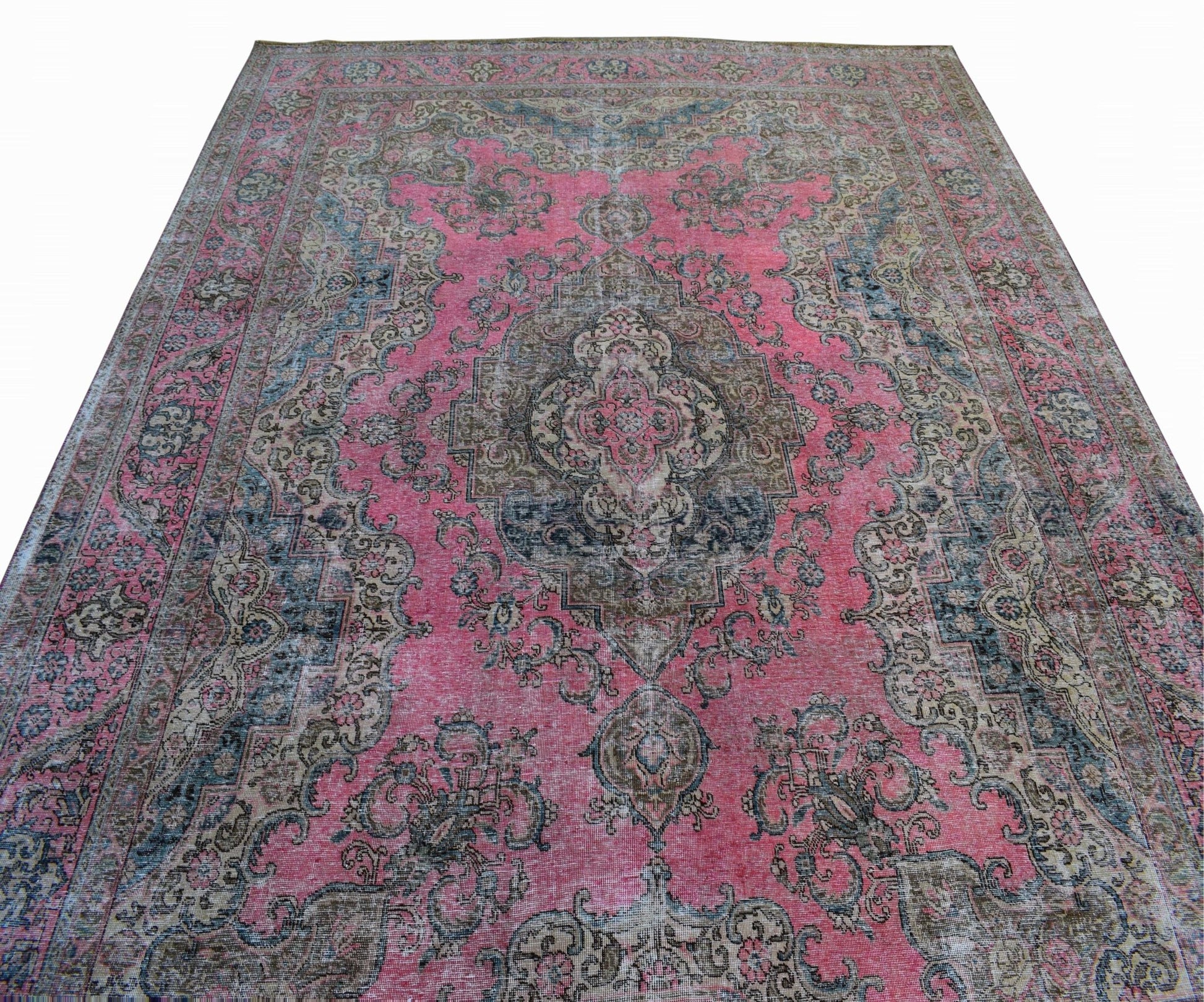 A vintage Persian Tabriz rug featuring a central floral medallion on a faded pink field.