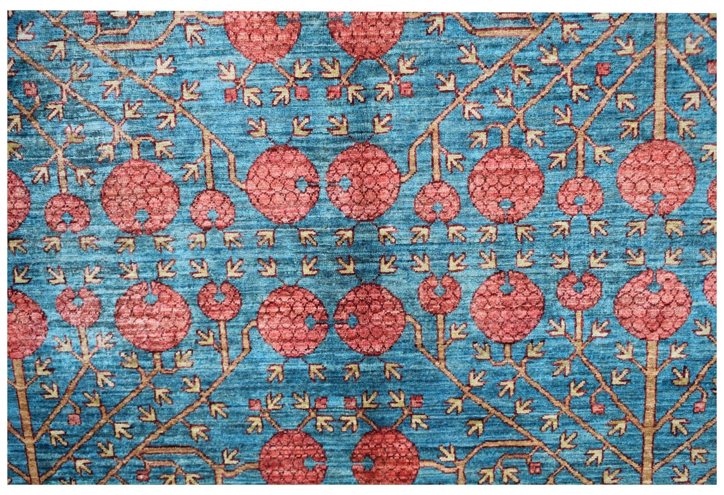 Handwoven Afghan rug featuring a repeating pomegranate motif in red on a blue background.