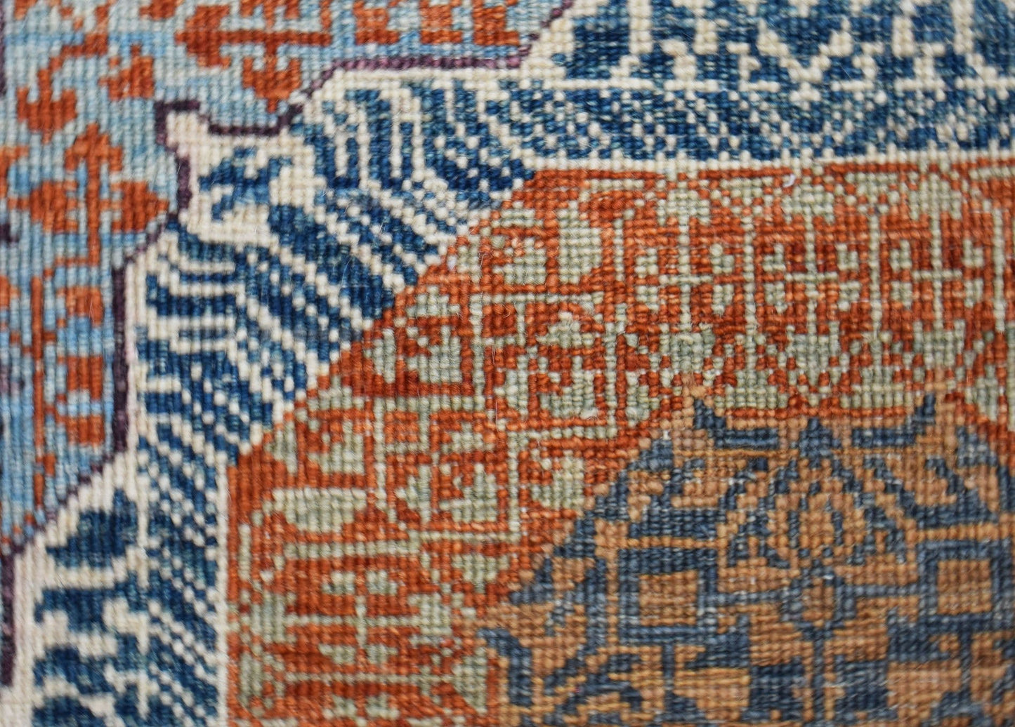 A close-up of a handwoven Afghan Balkh rug featuring intricate geometric patterns in blue and orange.