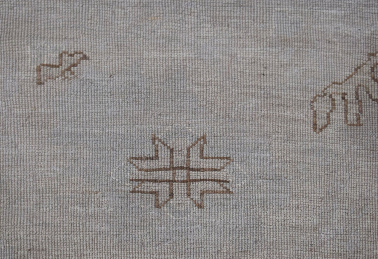 A handwoven Afghan Balkh rug featuring a minimalist geometric motif on a light wool background.