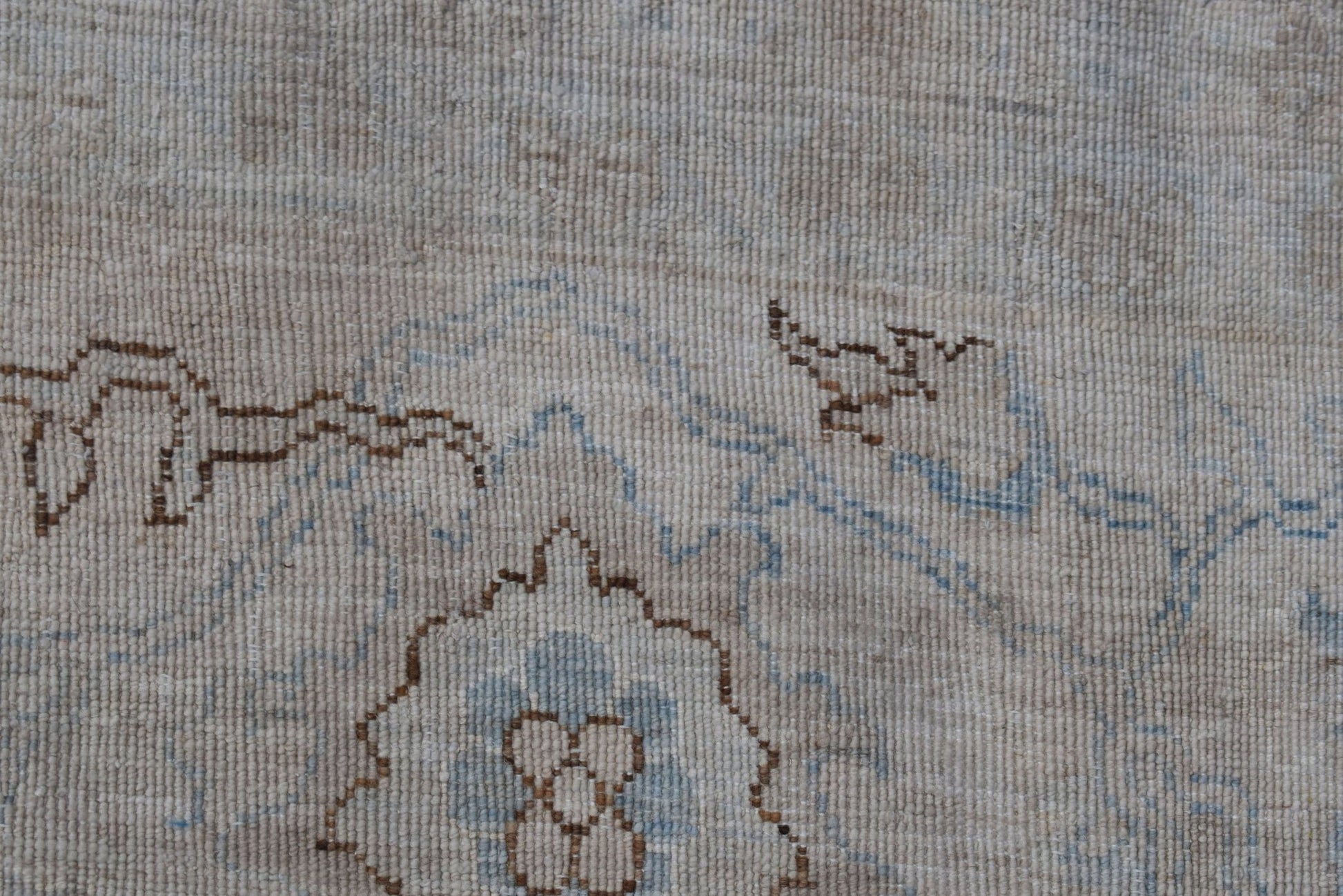 A close-up of a handwoven Afghan rug featuring a detailed brown and blue Mamluk pattern.