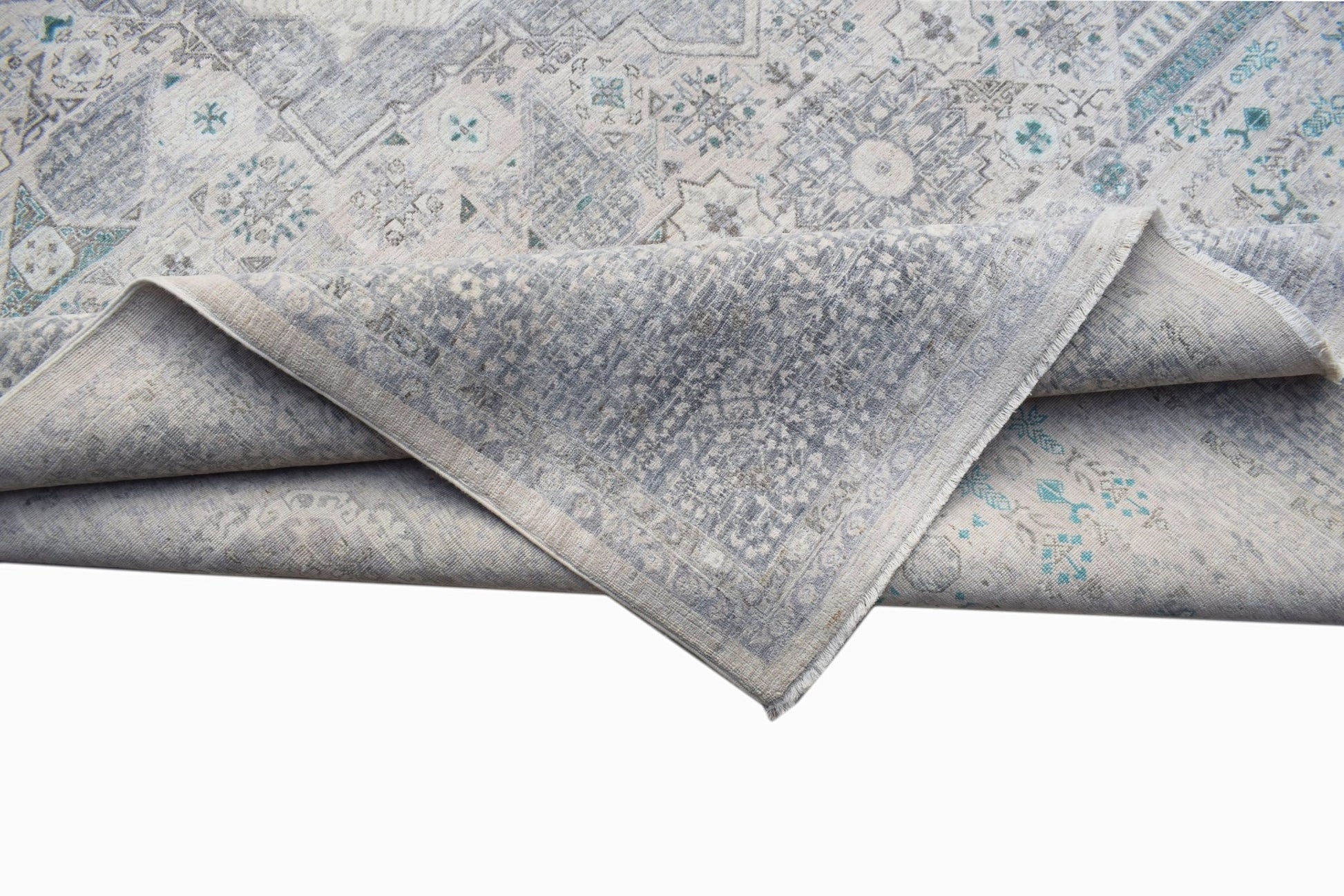 A handwoven Afghan Balkh rug with a grey and blue Mamluk pattern folded to show its texture.