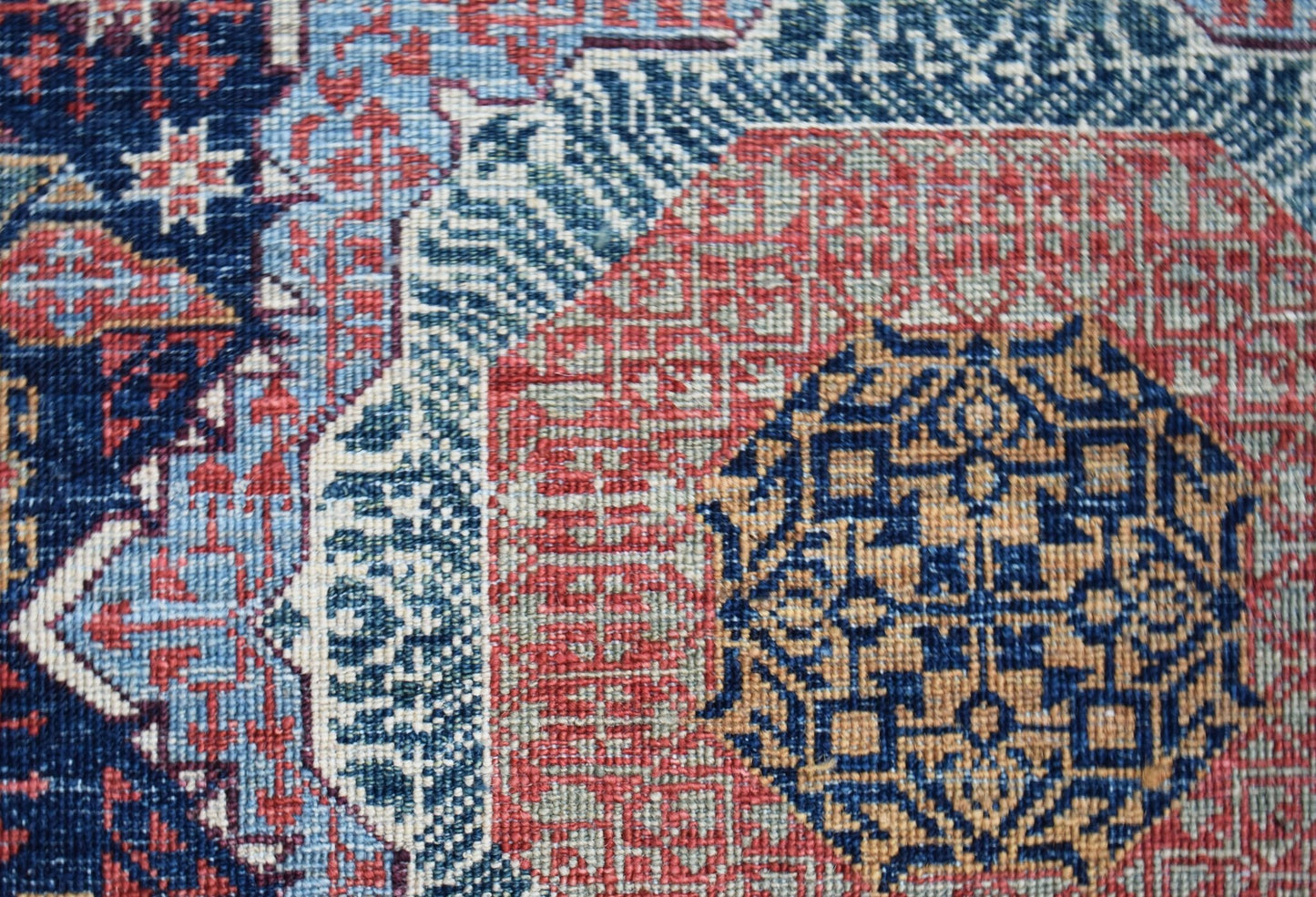 A close-up of a handmade Afghan Balkh rug featuring a detailed blue and red Mamluk medallion.