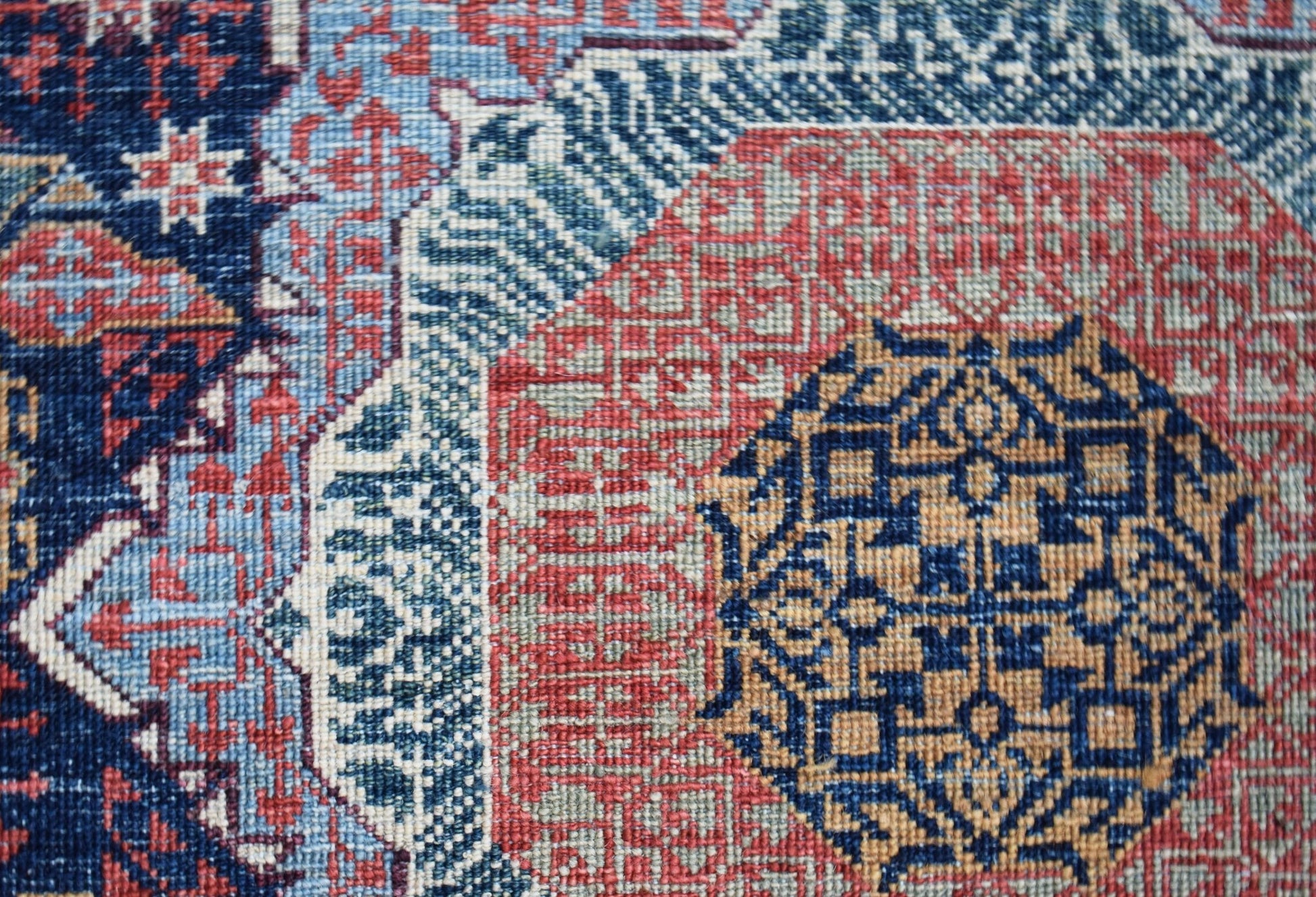 A close-up of a handmade Afghan Balkh rug featuring a detailed blue and red Mamluk medallion.