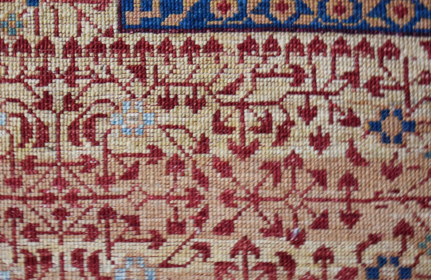 A close-up of a handmade Afghan Balkh rug featuring intricate red and blue geometric patterns.