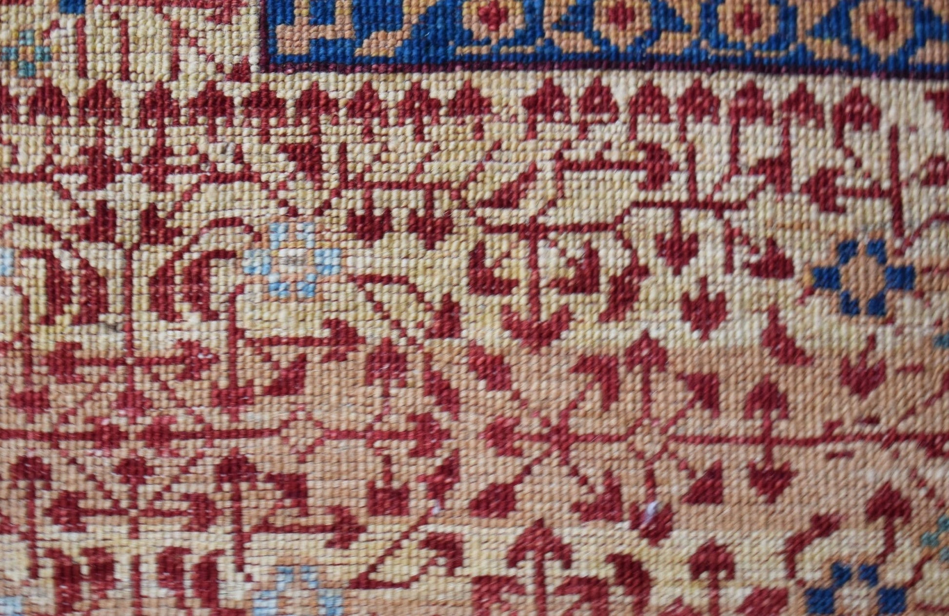 A close-up of a handmade Afghan Balkh rug featuring intricate red and blue geometric patterns.