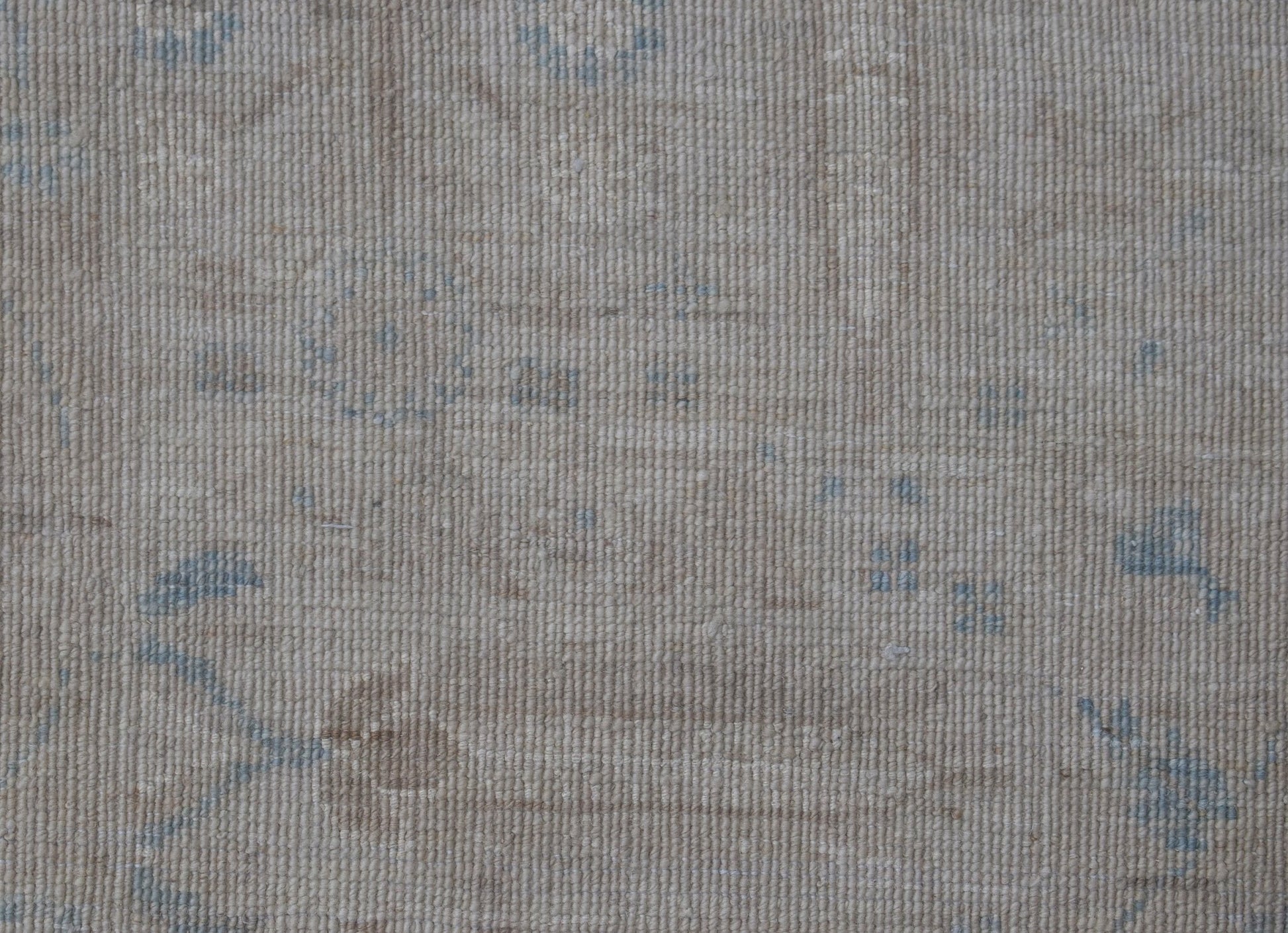 A handwoven Afghan Balkh rug featuring a subtle, traditional pattern in soft beige and blue tones.