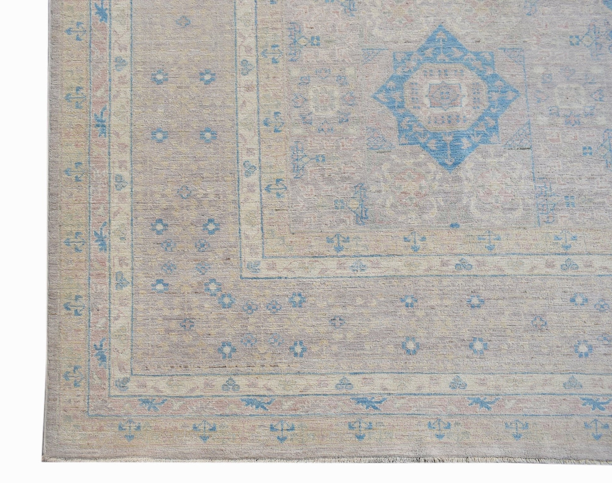 A handwoven Afghan Balkh rug featuring a light beige field with blue geometric floral motifs.